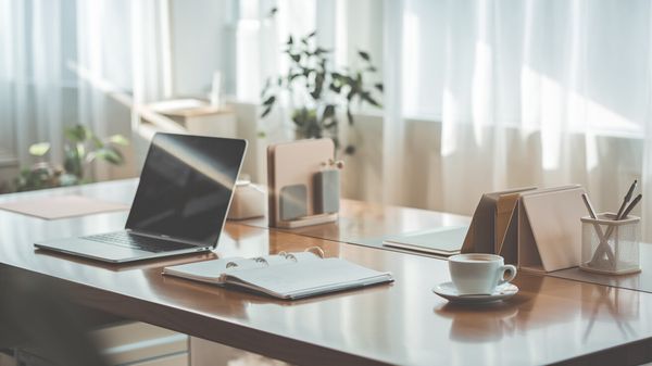 Minimalist office desk with laptop, planner, coffee, and plants in a bright, uplifting setting.